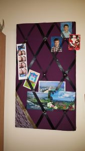 Purple photo board with black ribbon and shite lace in the corner.
